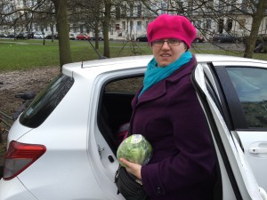 Jess by a car club car whilst holding a lettuce.
